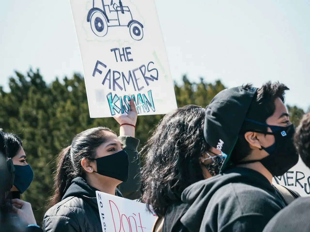 people standing and holding white and black banner during daytime